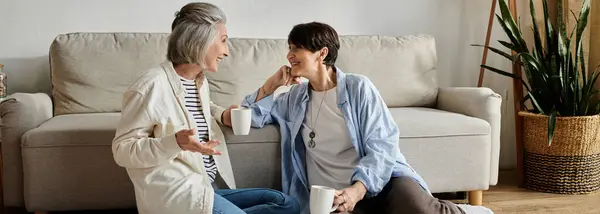 Two mature women sitting on floor, engaged in conversation. — Stock Photo