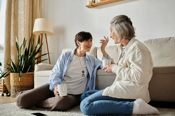 Two elderly women sitting on floor, engaged in conversation. — Stock Photo