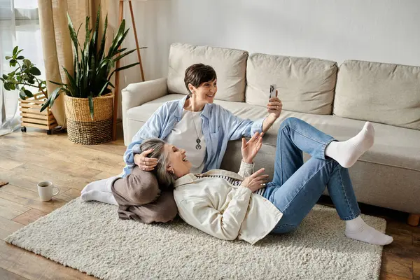 Two senior women playfully posing for a selfie on the floor. — Stock Photo