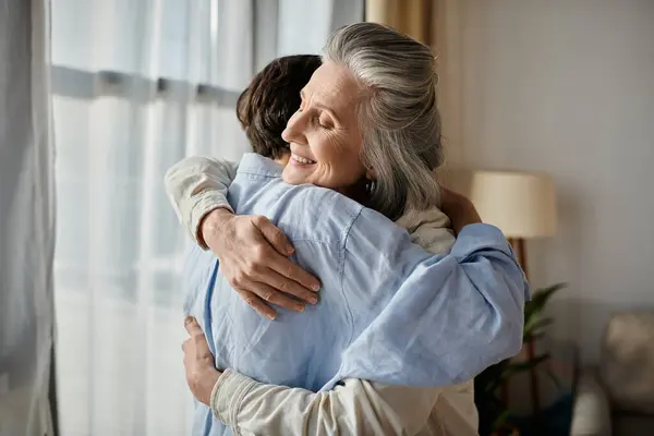 Zwei Frauen, die sich am Fenster liebevoll umarmen. — Stockfoto