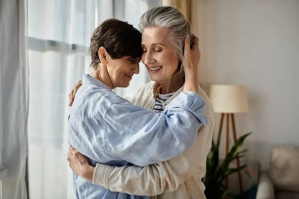 Duas mulheres idosas compartilham um abraço caloroso em sua acolhedora sala de estar. — Fotografia de Stock