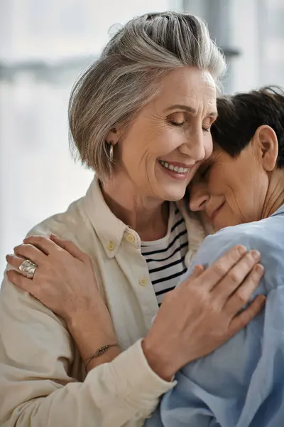 Two older women with loving expressions hugging each other tenderly. — Stock Photo