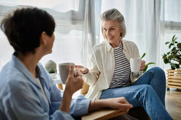 Zwei Seniorinnen unterhalten sich auf einem Sofa bei Kaffee. — Stockfoto