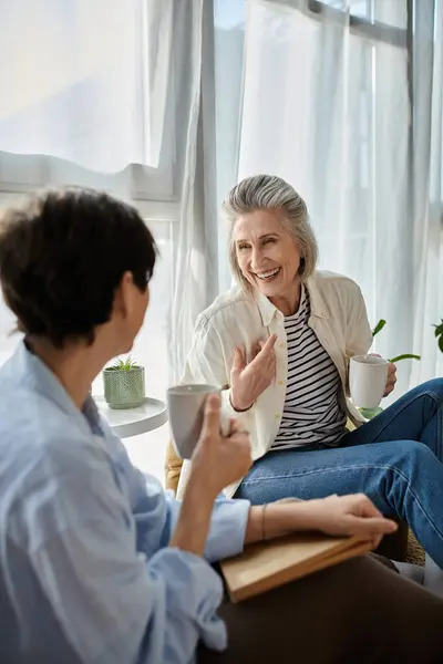 Two women deep in conversation, enjoying coffee together in a cozy room. — Stock Photo