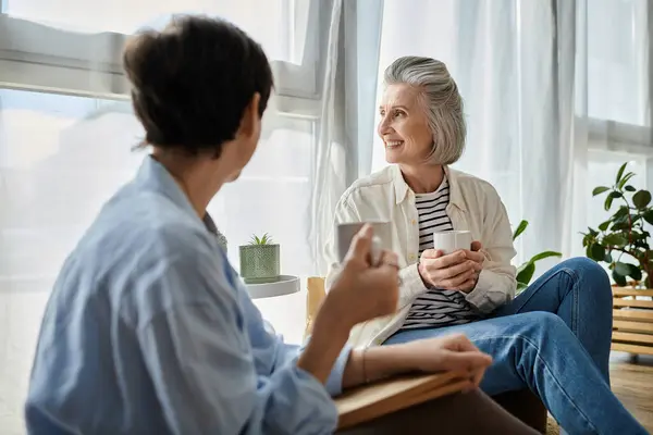Two women affectionately conversing in a chair, engrossed in each others words. — Stock Photo