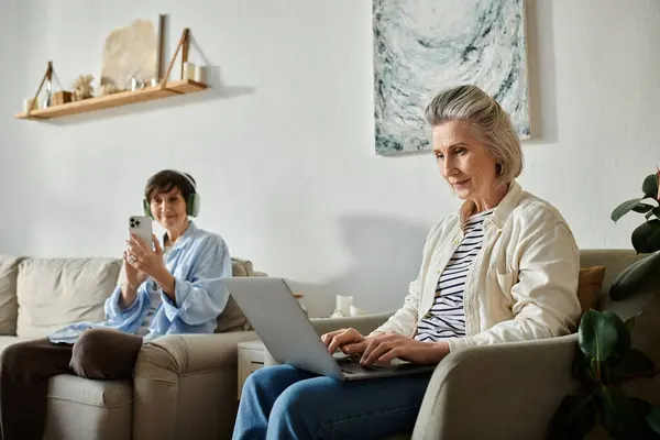 Two women enjoy a cozy moment on a couch, engaged with a laptop. — Stock Photo