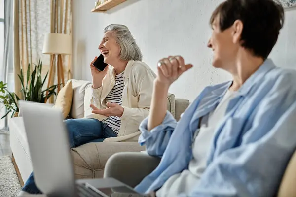 Two women chatting on phone while relaxing on couch. — Stock Photo