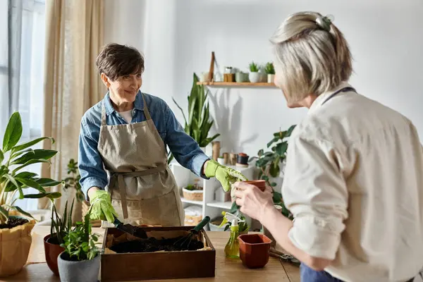 Zwei Frauen in Schürzen arbeiten gemeinsam in einem Garten unter der Sonne. — Stockfoto