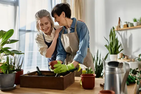 A loving mature lesbian couple wearing gardening aprons. — Stock Photo
