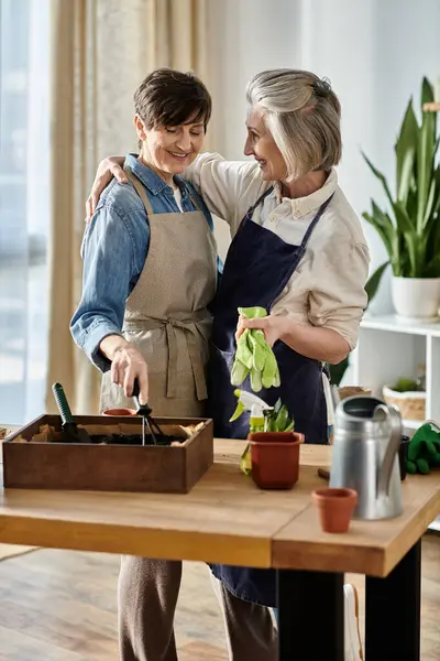 Дві жінки в фартухах стоять разом на кухні. — стокове фото