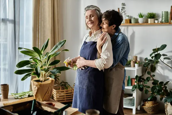 Two elderly women, a loving mature lesbian couple, share a warm hug in the kitchen. — Stock Photo