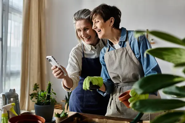 Two women in aprons capturing a moment on their phone. — Stock Photo