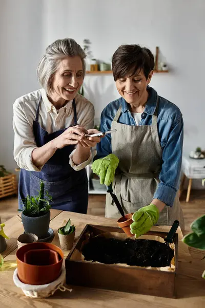 Two women in aprons tending a garden with care and unity. — Stock Photo
