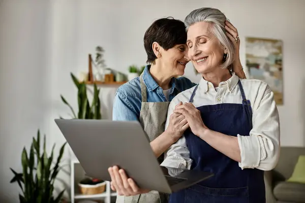 Dos mujeres, una pareja lesbiana madura amorosa, absorta en una pantalla de computadora portátil juntas. — Stock Photo