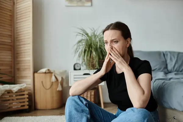 Middle-aged woman sitting, hand on nose, deep in thought. — Stockfoto