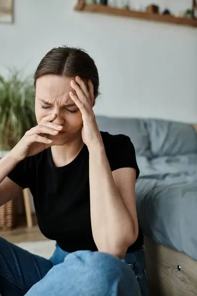 Middle-aged woman in distress, hands on face, sitting on floor. — Stock Photo