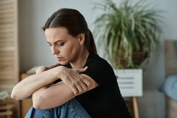 Middle-aged woman sitting on floor, hands on knees in deep thought. — Stock Photo