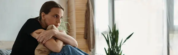 Middle-aged woman sits with crossed arms on a couch. — стоковое фото
