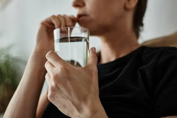 A middle-aged woman peacefully drinking water from a glass. — Stock Photo