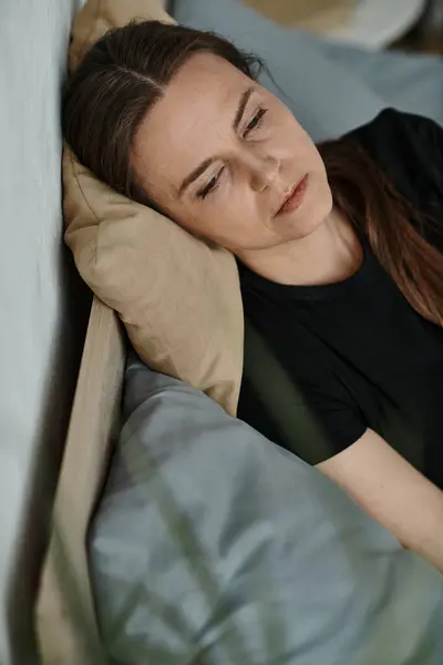 A middle-aged woman finds solace in bed, her eyes gently closed in peaceful repose. — Fotografia de Stock