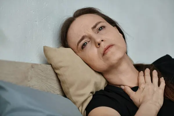Middle-aged woman lying in bed with hand on chest. — Stock Photo