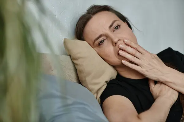 Middle-aged woman laying on a couch, hand on face. — Stock Photo