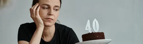 A woman joyfully holding a cake with a 40 candle on it. — Stock Photo