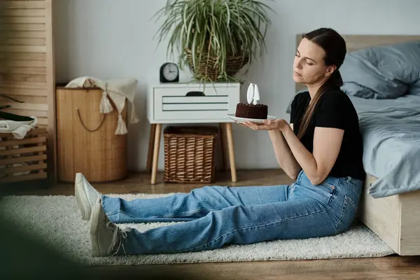 A woman in contemplation, seated with a cake in front of her. — стоковое фото