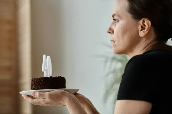 Woman holds cake with number, celebrating milestone. — стокове фото