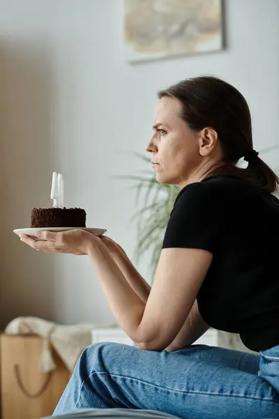 Woman sitting on couch, holding birthday cake. — Fotografia de Stock