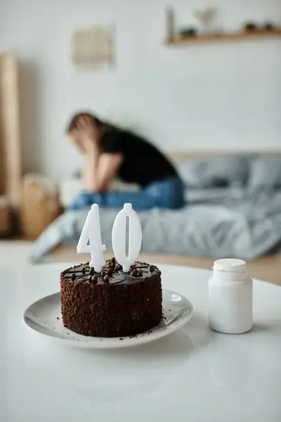 A woman sits in front of a 40th birthday cake on a table. — Fotografia de Stock