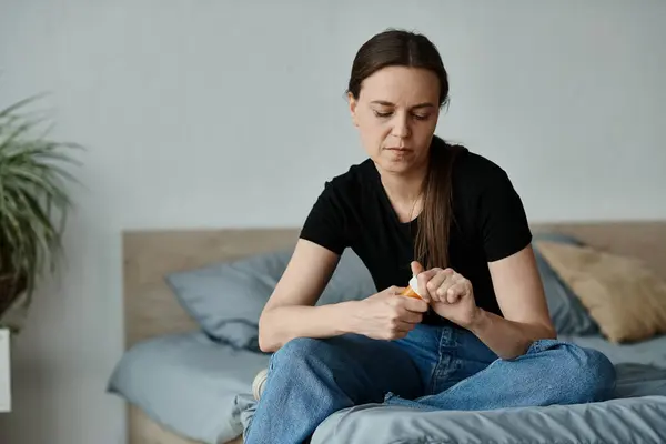Middle-aged woman sitting on bed with hands on knees in thoughtful contemplation. — Stock Photo