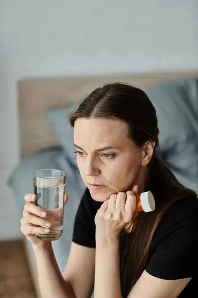 A woman peacefully holding a glass of water on her bed. — Fotografia de Stock