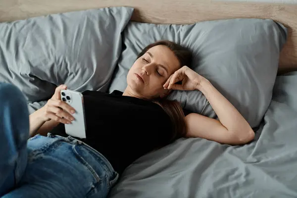 A woman lies in bed holding a phone. — Stock Photo