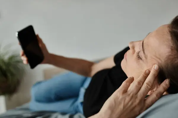 A middle-aged woman in repose, holding her phone. - foto de stock