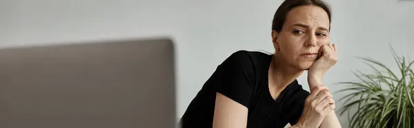 A middle-aged woman sits in front of her laptop, connecting to an online therapy session. — Stock Photo