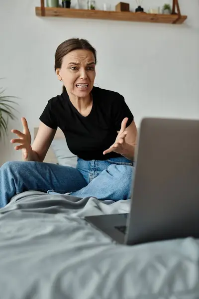 A woman finds solace sitting on a bed with a laptop. — Foto stock