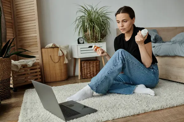 A middle-aged woman sits on the floor with a laptop, seeking online therapy support during a mental breakdown. — стокове фото