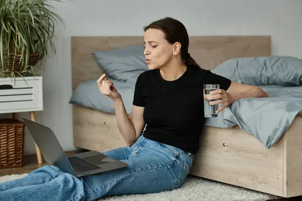 A woman, laptop, and water glass. - foto de stock