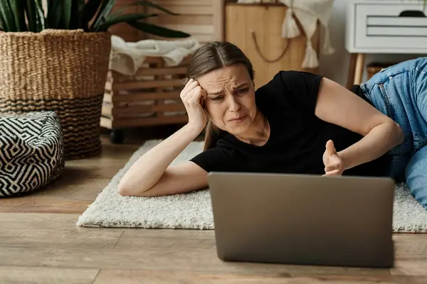 A woman in introspection, lying on the floor fixated on her laptop screen. — Foto stock