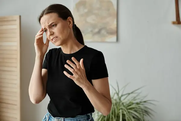 Middle-aged woman with a headache in her home, seeking online therapy during a mental breakdown. — стокове фото