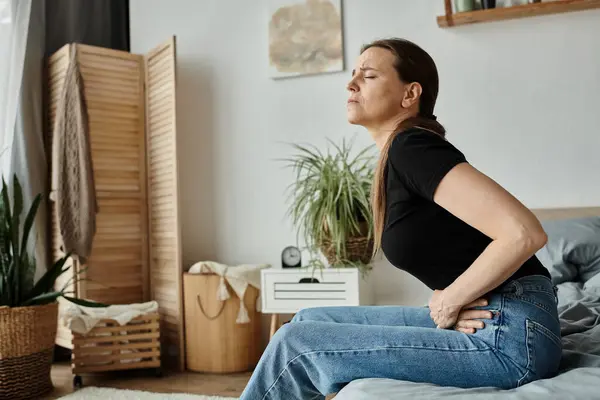 A woman sitting on a bed, visibly in discomfort due to depression. — Foto stock