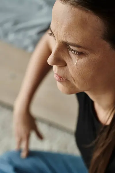A middle-aged woman sits and cries, struggling with depression. — стоковое фото