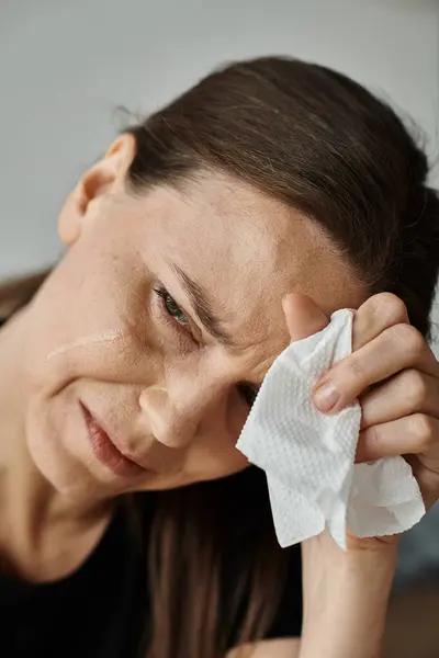Middle aged woman wiping her face with a tissue during a moment of emotional release. — Stockfoto