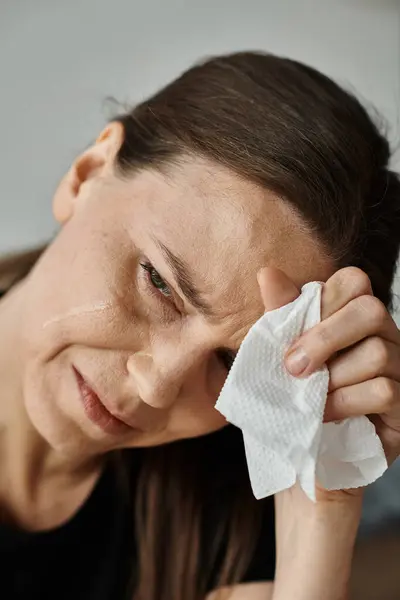 Middle aged woman wiping her face with a tissue during a moment of emotional release. — стоковое фото