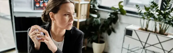A woman sits at a desk in an office, overwhelmed and contemplative. — стоковое фото