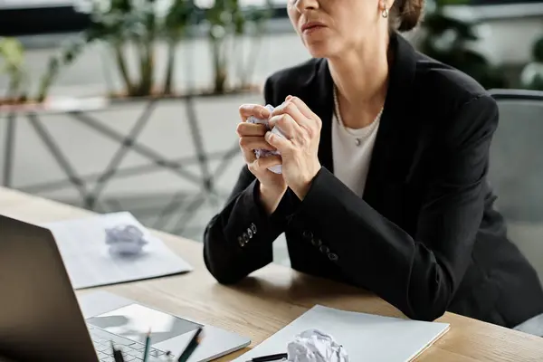 A middle-aged woman in distress, sitting at a desk with a laptop, experiencing a mental breakdown. — Fotografia de Stock