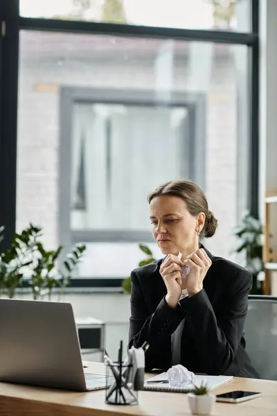 Middle-aged woman experiences stress working on laptop at desk. — стоковое фото