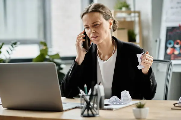 A middle-aged woman talks on the phone at her desk, showing signs of stress and mental fatigue. — Stock Photo