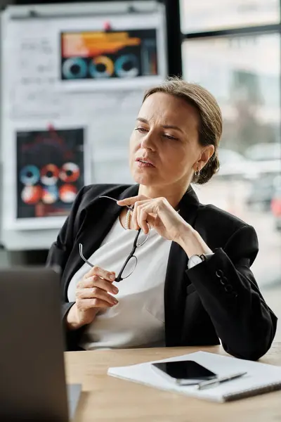 Middle-aged woman sitting at a desk, overwhelmed by stress while working on a laptop. — Fotografia de Stock